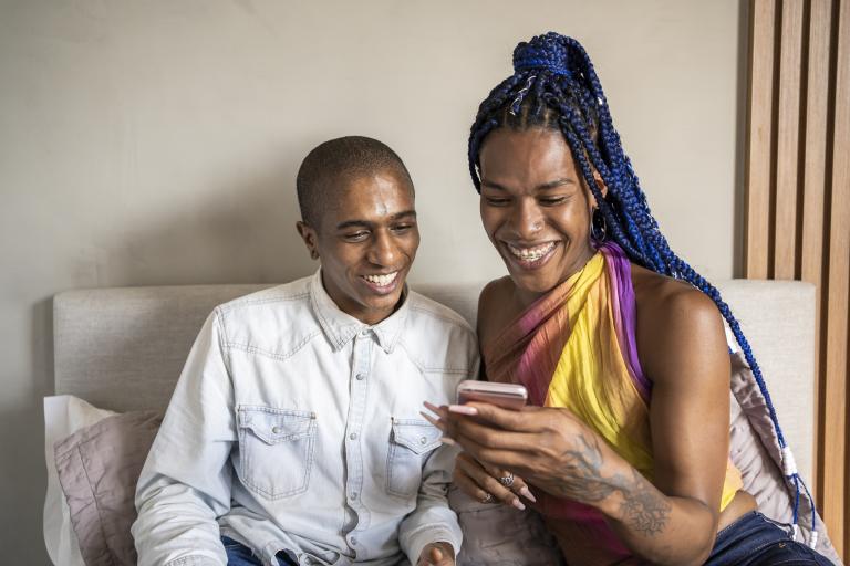 Two adults looking at a mobile phone and laughing