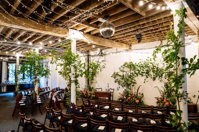 Chairs in semi circle surrounded by plants, lights and building walls