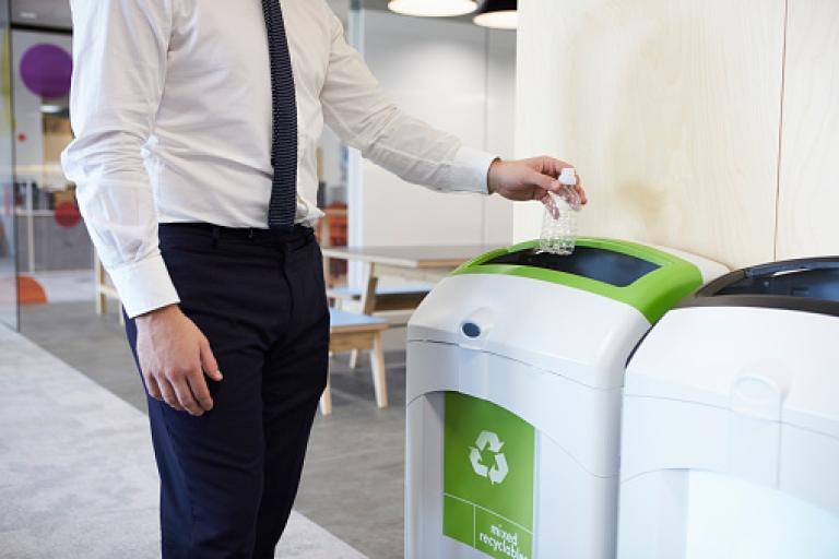 Person recycling bottle in corporate office