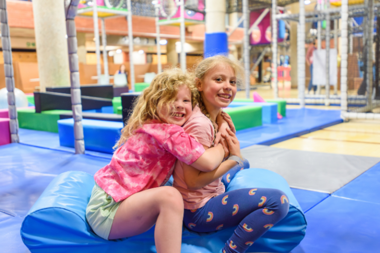 Smiling children playing on a soft play mat