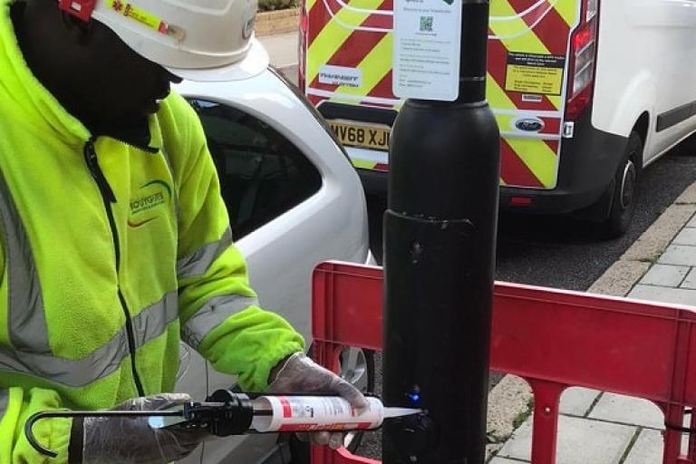 Worker installs electric vehicle charge point on lampost