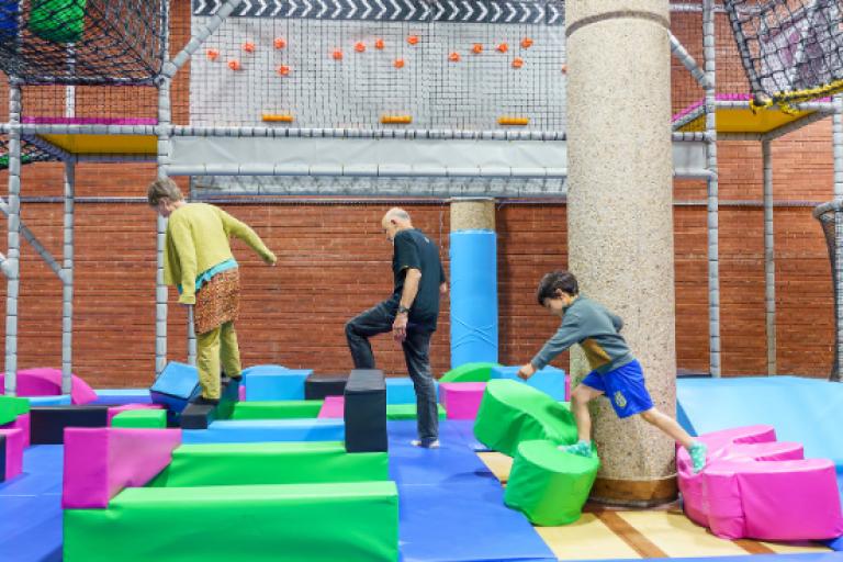 Children accompanied by adult playing on foam play gym