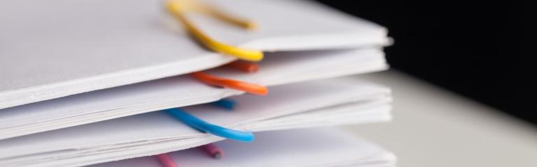 Pile of documents separated with colourful paperclips