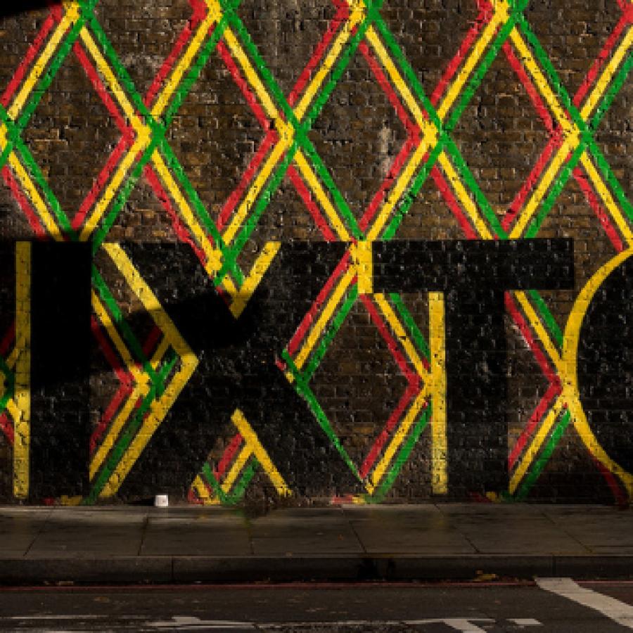 Artist painted Brixton in black and a mixed colour border on a wall under Brixton Rail bridge