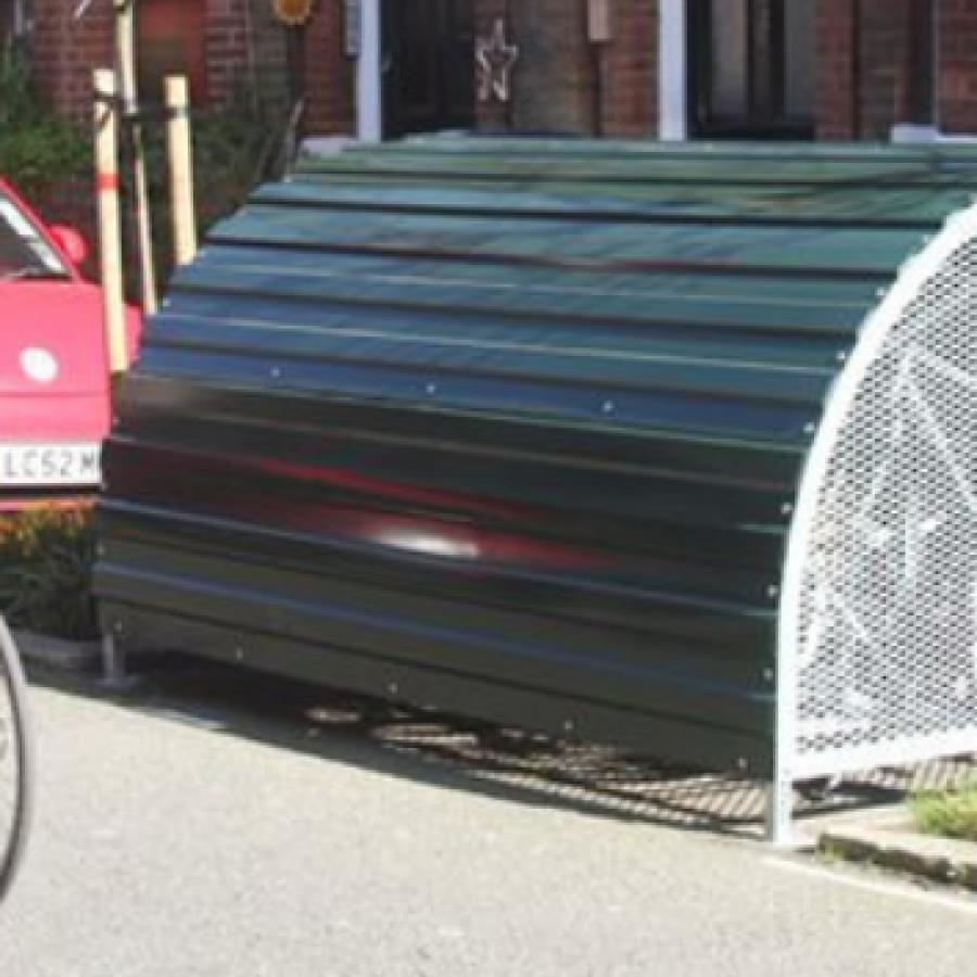 Person wearing a helmet cycling past a cycle hangar on street in Lambeth