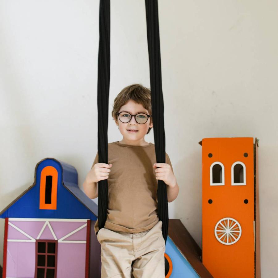 a kid standing beside a built cardboard castle