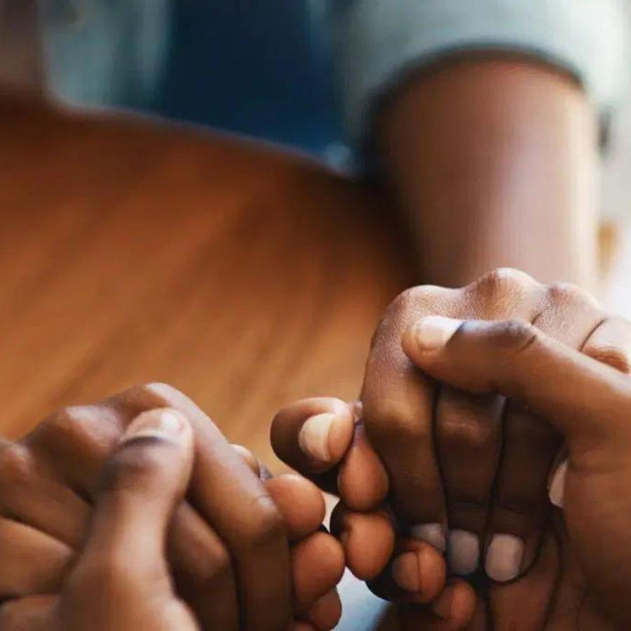 photo from mental health uk of 2 people holding hands across a table